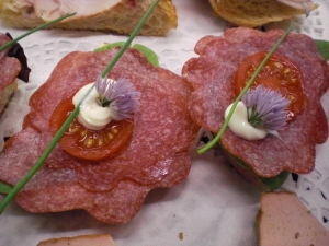 Lye roll bite with Milanese salami and chive blossoms